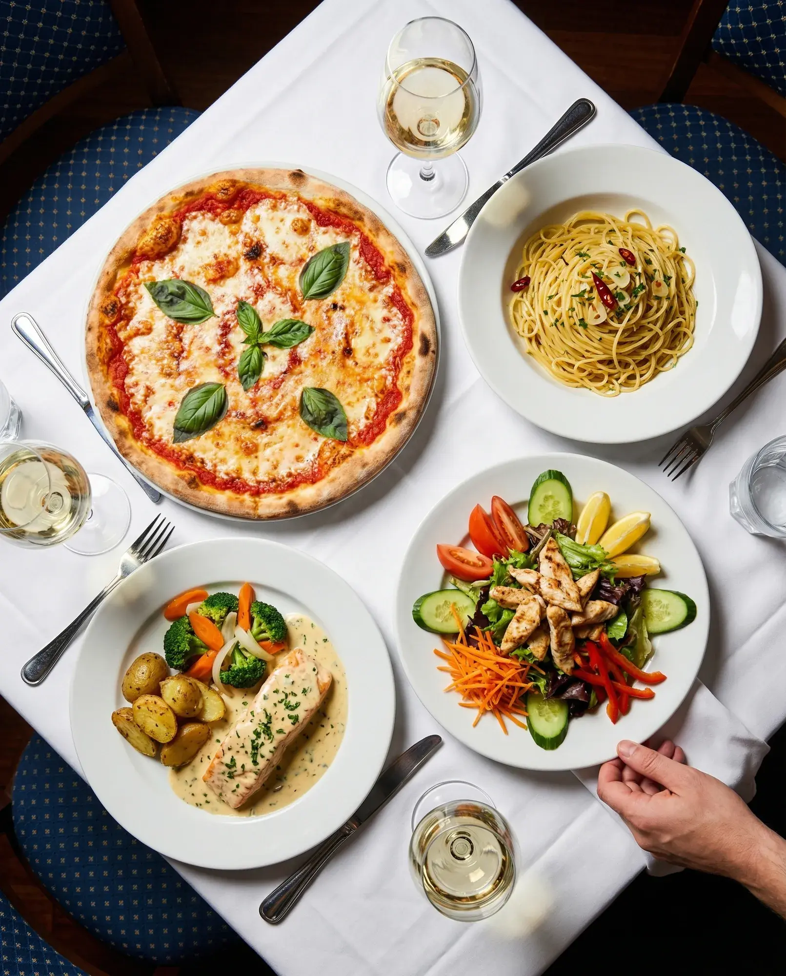 Pizza, Pasta, Salat und Lachs auf einem gedeckten Tisch bei La Commedia.