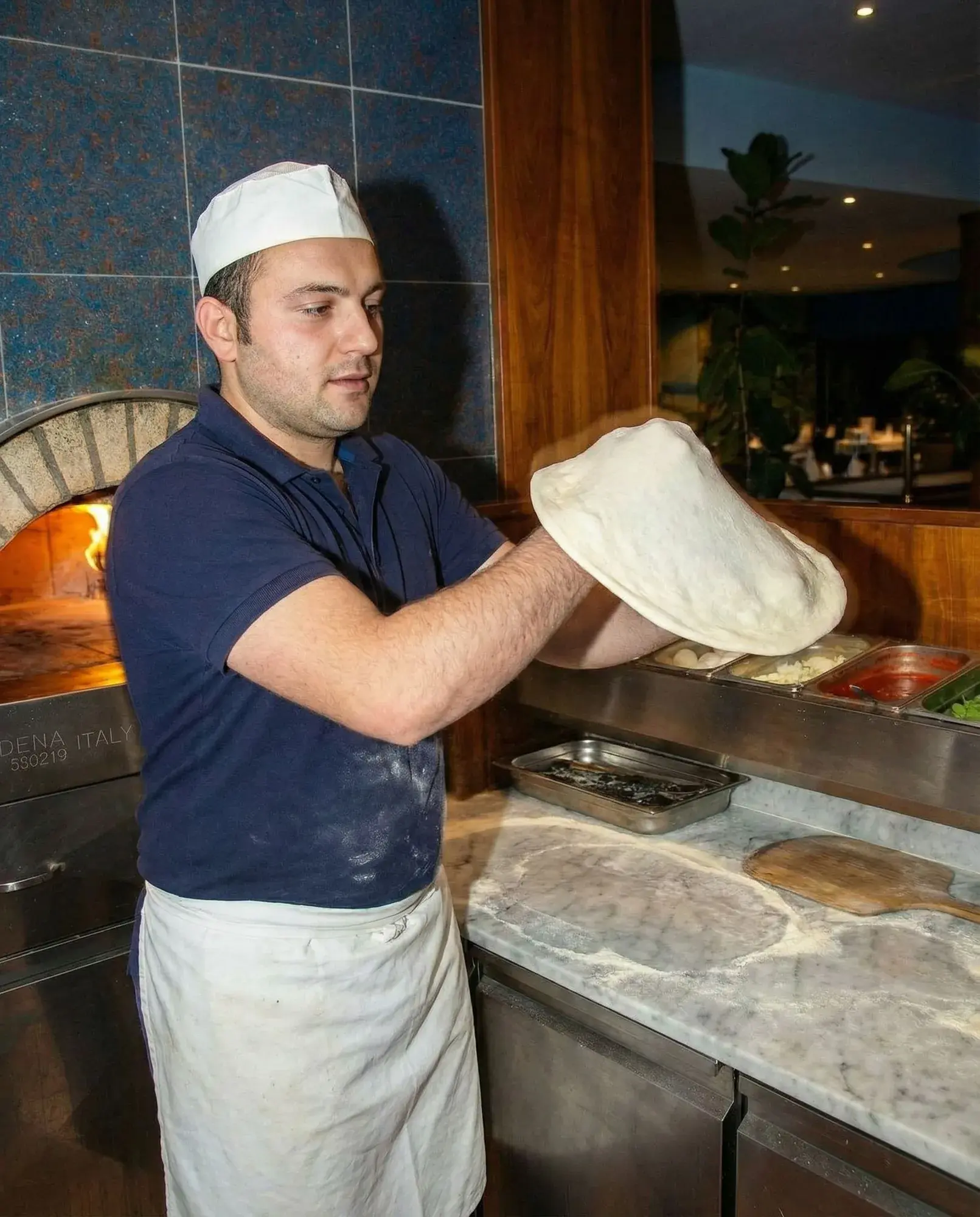 Pizzateig wird von Hand in Form gebracht.